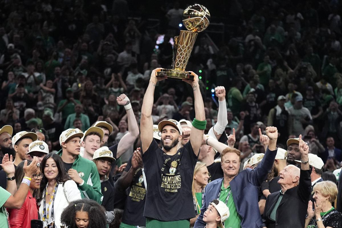 Boston Celtics forward Jayson Tatum holds up the Larry O'Brien Championship Trophy as he celebrates with his team after winning the NBA Championship over the Dallas Mavericks on June 17, 2024. Charles Krupa/Associated Press